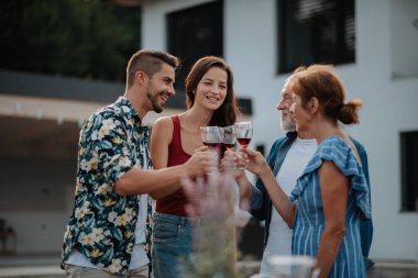 Bahar aile barbeküsü sırasında aile şaraba kadeh kaldırıyor. Aile bahçesi partisi.