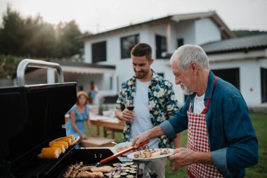 Kayınpederim ve damadım aile barbeküsü için yemek hazırlıyorlar. Bahar bahçesi partisi.