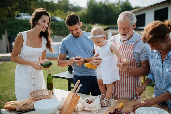 Üç nesildir aile bahar hafta sonu barbeküsü için yemek hazırlıyor. Bahçe partisi.