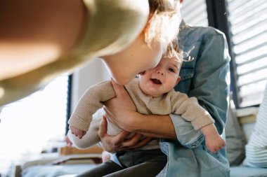 Büyük abla babasının kollarında yeni doğan erkek kardeşe bakıyor. Büyük aile kavramı.