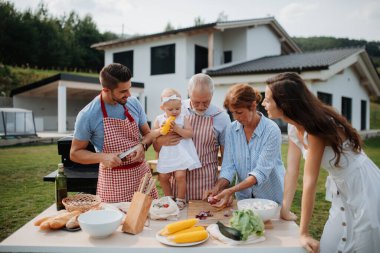 Üç nesildir aile bahar hafta sonu barbeküsü için yemek hazırlıyor. Bahçe partisi.