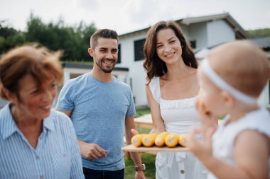 Küçük kız, aile barbekü partisinde mısır yiyor..