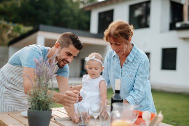 Üç nesildir aile bahar hafta sonu barbeküsü için yemek hazırlıyor. Bahçe partisi.