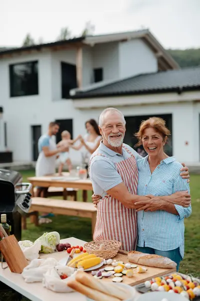 Yaşlı evli çift aile barbeküsü için yemek hazırlıyor. Bahar bahçesi partisi.