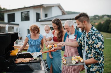 Üç nesildir aile bahar hafta sonu barbeküsü için yemek hazırlıyor. Bahçe partisi.