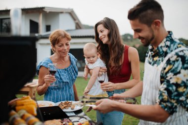 Üç nesildir aile bahar hafta sonu barbeküsü için yemek hazırlıyor. Bahçe partisi.