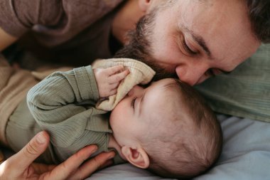 Baba bebeği uykuya yatırır, beşiğinde yanında yatar ve onu sakinleştirir..