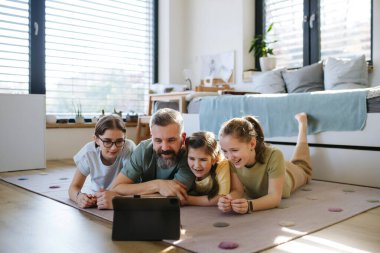 Tabletten televizyon izleyen üç kızlı babanın portresi. Kız baba kavramı.