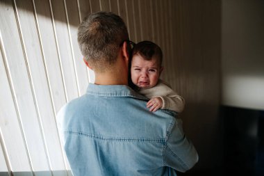 Baba ağlayan oğlunu teselli ediyor, onu kollarına alıyor..