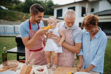 Üç nesildir aile bahar hafta sonu barbeküsü için yemek hazırlıyor. Bahçe partisi.