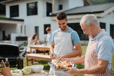 Kayınpederim ve damadım aile barbeküsü için yemek hazırlıyorlar. Bahar bahçesi partisi.