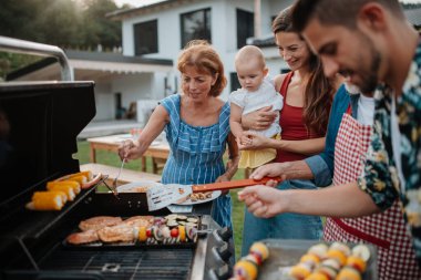 Üç nesildir aile bahar hafta sonu barbeküsü için yemek hazırlıyor. Bahçe partisi.