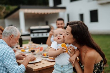 Aile masada oturuyor ve bahar aile barbeküsü sırasında lezzetli yemekler yiyor. Aile bahçesi partisi..
