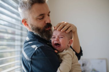 Baba ağlayan oğlunu teselli ediyor, onu kollarına alıyor..
