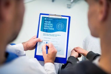 Ruh sağlığı değerlendirme formunu dolduran doktor ve genç hastalara yakın çekim.