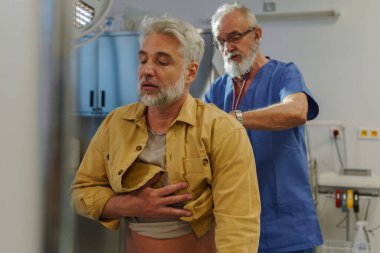 Doktor hastayı muayene ediyor, steteskopla nefes alıyor..