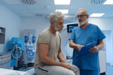Doktor tomografi sonuçlarını hastane ortamındaki erkek hastaya açıklıyor.