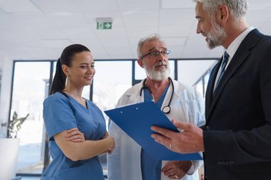 Tıbbi satış temsilcisi doktorlara yeni ilaçlar sunuyor. Hastane koridorunda ayakta duruyor. Hastane ayarları.