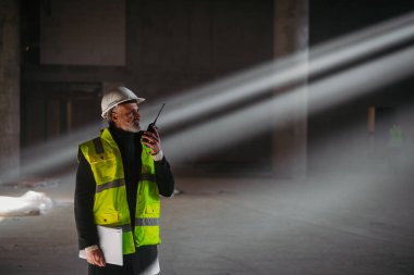 İnşaat ustası bina teftişi sırasında telsizden talimat veriyor..