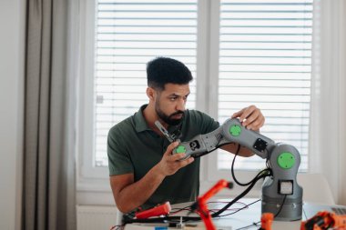 Genç mühendis evde bir robotik kol yapıyor ve programlıyor. Robot konsepti.