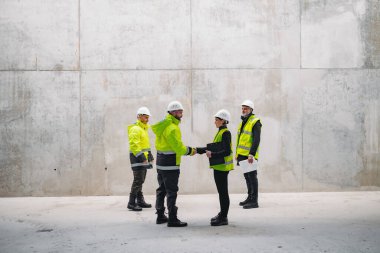 Modern inşaat alanında mühendis inşaat müdürüyle el sıkışıyor..