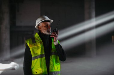 İnşaat ustası bina teftişi sırasında telsizden talimat veriyor..