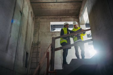 İnşaat yöneticilerinin bina planlarını veya proje planlarını gözden geçirmelerinin arka görünümü.