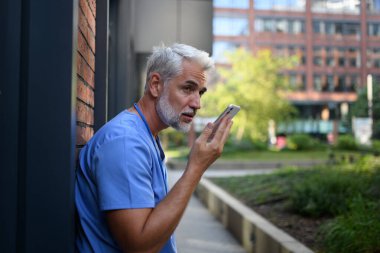 Doktor ailesine geç saatlere kadar işte kalması gerektiğini söyleyen bir sesli mesaj kaydediyor..