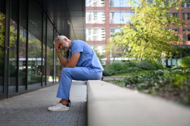 Hüsrana uğramış ve bitkin düşmüş bir doktor, hastanenin dışında oturmuş, kendini kötü hissediyor. Ruh sağlığı sorunları.