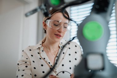 Kadın mühendis evde bir robotik kol yapıyor ve programlıyor. Robot konsepti.