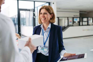 Kadın tıbbi satış temsilcisi. Doktora ilaç sunuyor. Hastane koridorunda duruyor..