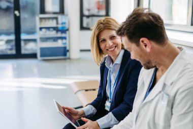 İlaç mümessili ve doktor ilaç örnekleri ve reçeteleri tartışıyor, hastane bekleme odasında oturuyor..