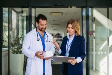 Kendine güvenen kadın tıbbi satış temsilcisi doktorlara ilaç ürünlerini tanıtıyor. Hastane ayarları.