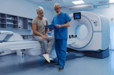 Doktor tomografi sonuçlarını hastane ortamındaki erkek hastaya açıklıyor.