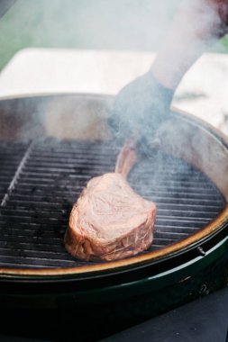 Izgarada lezzetli bir Tomahawk bifteği kızartıyorum..