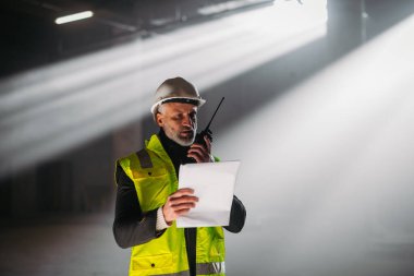 İnşaat ustası bina teftişi sırasında telsizden talimat veriyor..