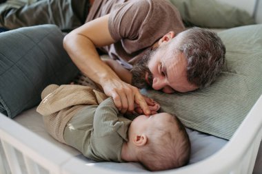 Baba bebeği uykuya yatırır, beşiğinde yanında yatar ve onu sakinleştirir..