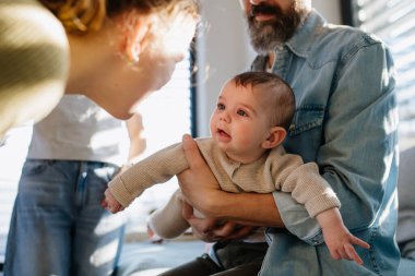 Büyük abla babasının kollarında yeni doğan erkek kardeşe bakıyor. Büyük aile kavramı.