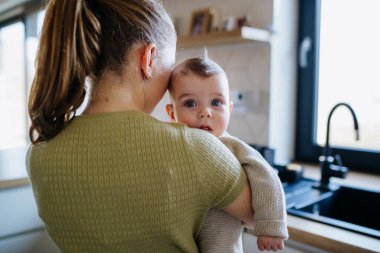 Abla kucağında küçük kardeşini tutuyor, ona bakıyor..