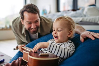 Babası küçük oğluyla gitar çalıyor, eğleniyor..