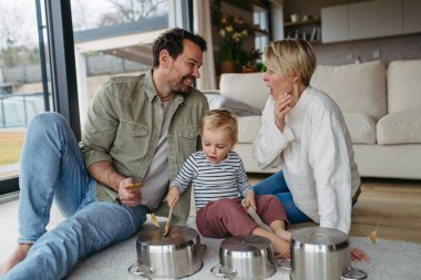 Anne babası ve küçük oğlu mutfak çanaklarında davul çalıyorlar..