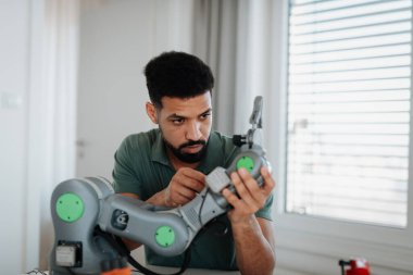 Genç mühendis evde bir robotik kol yapıyor ve programlıyor. Robot konsepti.