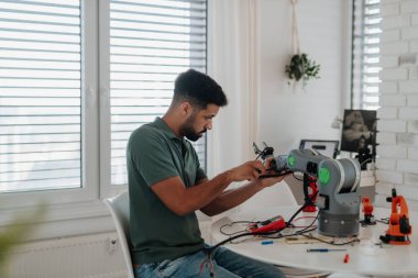 Genç mühendis evde bir robotik kol yapıyor ve programlıyor. Robot konsepti.