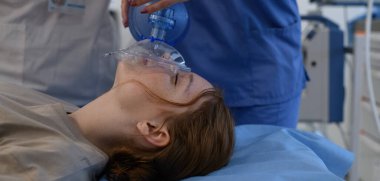 Hastane personeli, hastanedeki baygın genç kıza oksijen maskesi takıyor. Tıbbi prosedür.