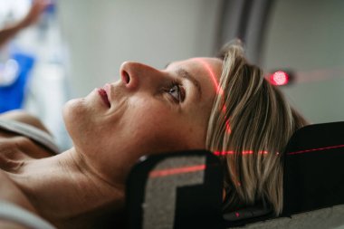 Hasta beyin taraması için bilgisayarlı tomografiye yerleştirildi. Kırmızı lazer çizgileri.