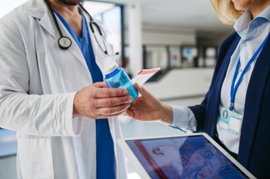 Kadın tıbbi satış temsilcisi doktorlara ilaç ürünlerini tanıtıyor. Hastane ayarları.