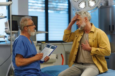 Muayene masasında oturan hasta, doktorlara sağlık sorunları ve semptomları anlatıyor..