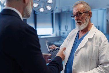 Kendine güvenen tıbbi satış temsilcisi doktorlara ilaç ürünlerini tanıtıyor. Hastane ayarları.