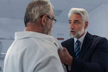 Sağlık çalışanlarına karşı şiddet. Hasta agresif, doktorla kavga ediyor, onu ceketinden tutuyor..