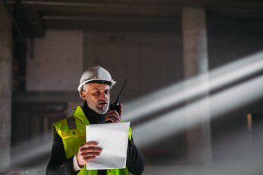 İnşaat ustası bina teftişi sırasında telsizden talimat veriyor..